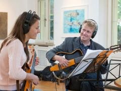 Ein Musikschullehrer gibt einer Schülerin Gitarrenunterricht